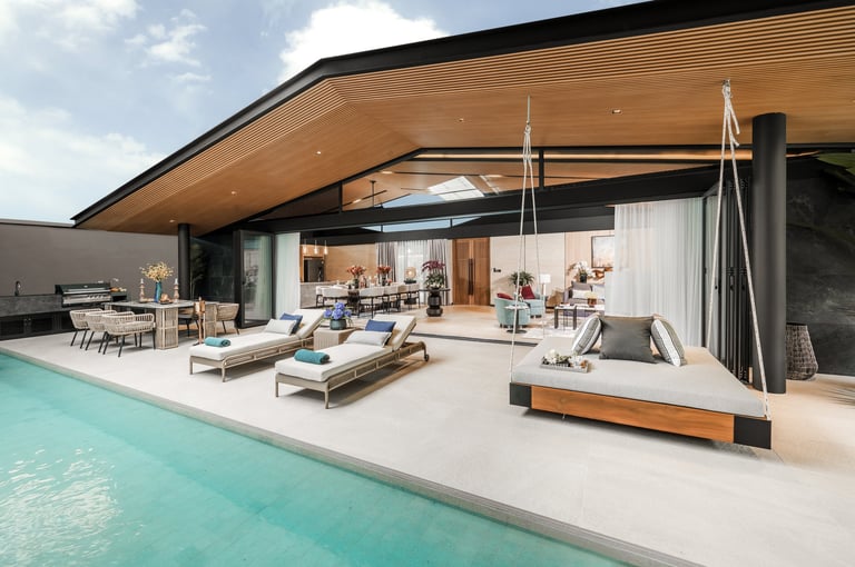 Modern home with curved wooden ceiling, turquoise pool, and open-concept living space with lounge chairs and built-in seating