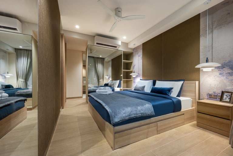 Modern bedroom with blue bedding, wooden bed frame, large mirror, and accent wall featuring contemporary furnishings and warm lighting