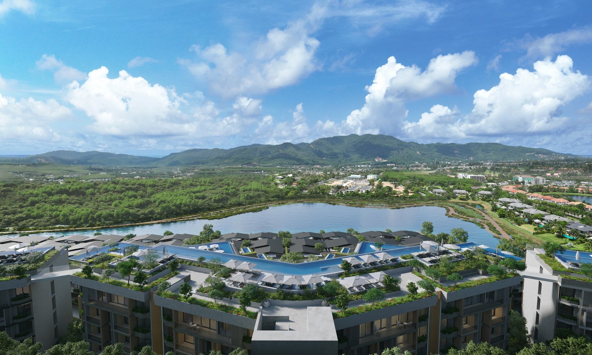 Aerial view of a large blue water park complex surrounded by green landscape, mountains, and residential areas