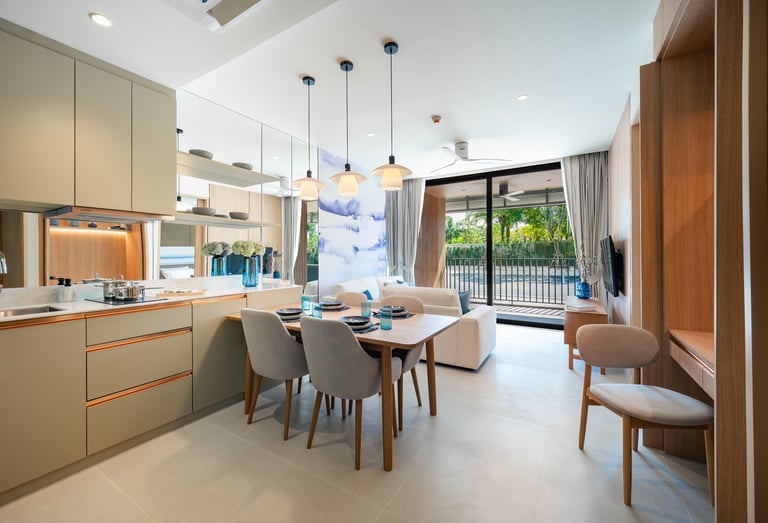 Modern open-plan kitchen and dining area with light wood finishes, dining table with chairs, and sliding doors opening to a balcony with greenery