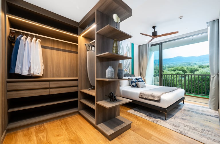 Modern bedroom with built-in wooden wardrobe, bed, shelving unit, and scenic mountain view from balcony