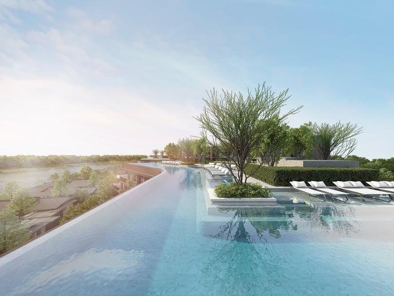 Infinity pool overlooking wetlands with ornamental grasses and lounge chairs under blue sky