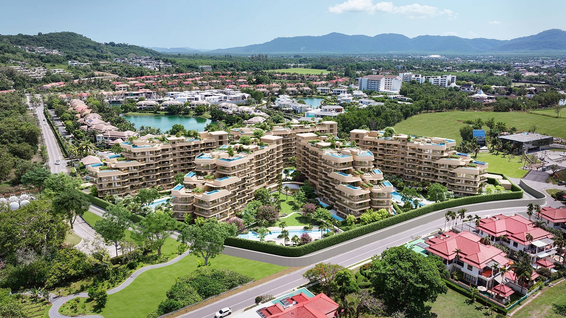 Aerial view of a residential complex with multiple apartment buildings, landscaped grounds, pools, and mountains in the distance