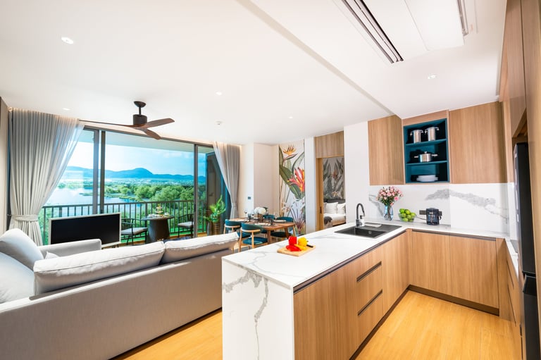 Modern open-plan kitchen and living room with wooden cabinetry, marble island, large windows overlooking mountain views, and comfortable seating area