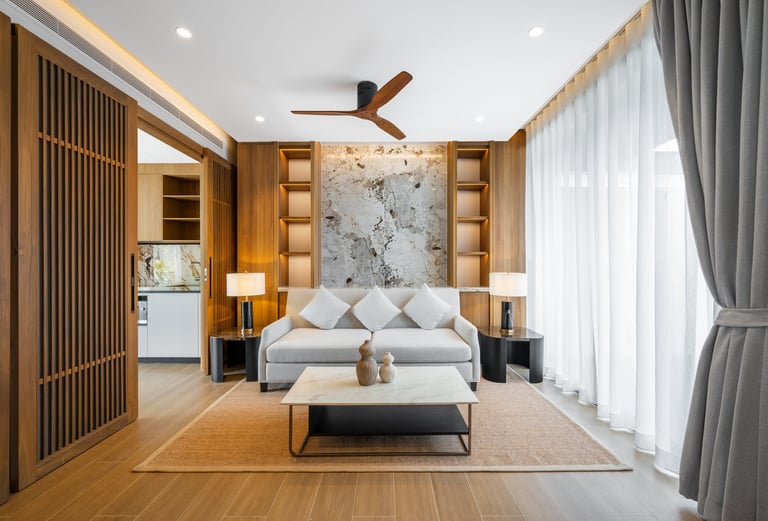 Modern bedroom with wooden cabinetry, gray upholstered bed, marble accent wall, and large windows with gray curtains