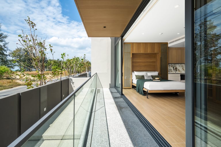 Modern bedroom balcony overlooking landscaped garden with glass railing and open view to interior bedroom space