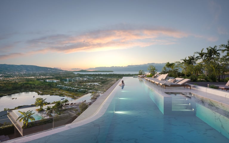 Infinity pool overlooking a valley landscape at sunset with palm trees and lounge chairs
