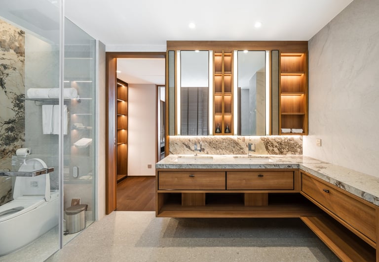 Modern luxury bathroom with marble countertop vanity, illuminated mirror cabinets, wooden accents, glass shower enclosure, and spa-like design