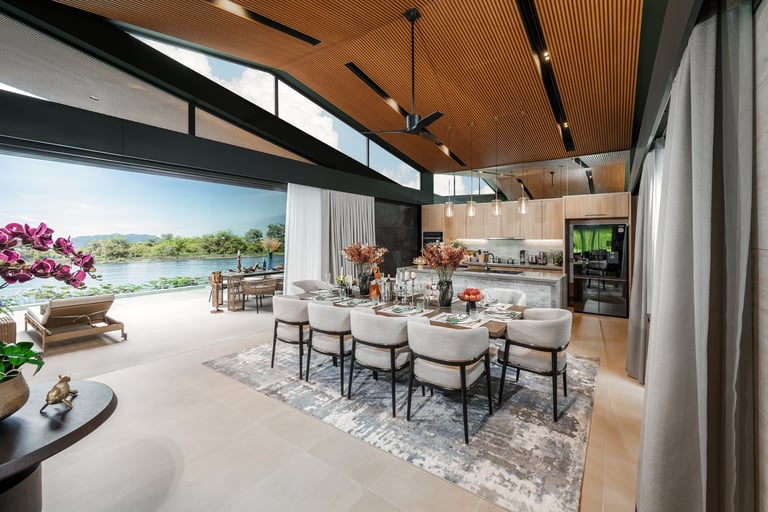 Modern open-concept kitchen and dining area with floor-to-ceiling windows overlooking a waterfront landscape, featuring wooden ceiling and contemporary furnishings.