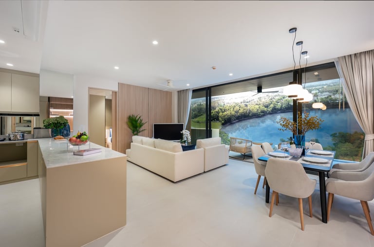 Modern open-plan living space with kitchen, dining, and lounge area overlooking a blue water view through large windows