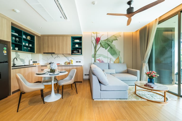 Modern open-plan apartment with kitchen, dining area, and living room featuring wooden floors, light blue sofa, and contemporary furnishings