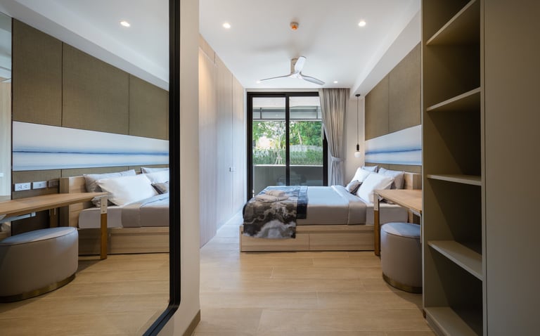 Modern bedroom with twin beds, wooden flooring, olive green storage cabinets, and glass doors overlooking a balcony.